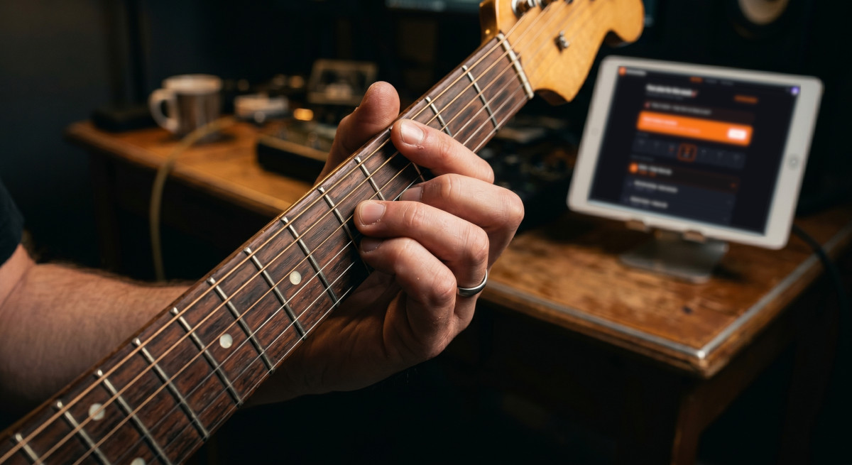Guitarist practicing with InstrumentGym on tablet